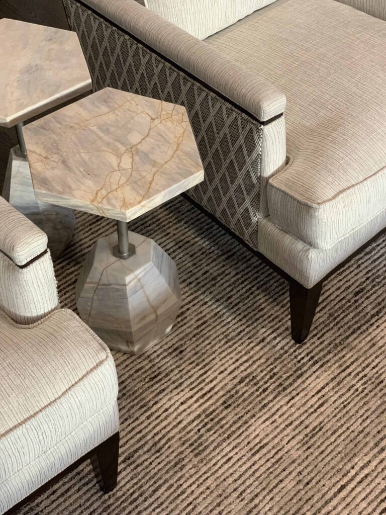 Detail shot of custom club chairs with marble side tables and textured rug.