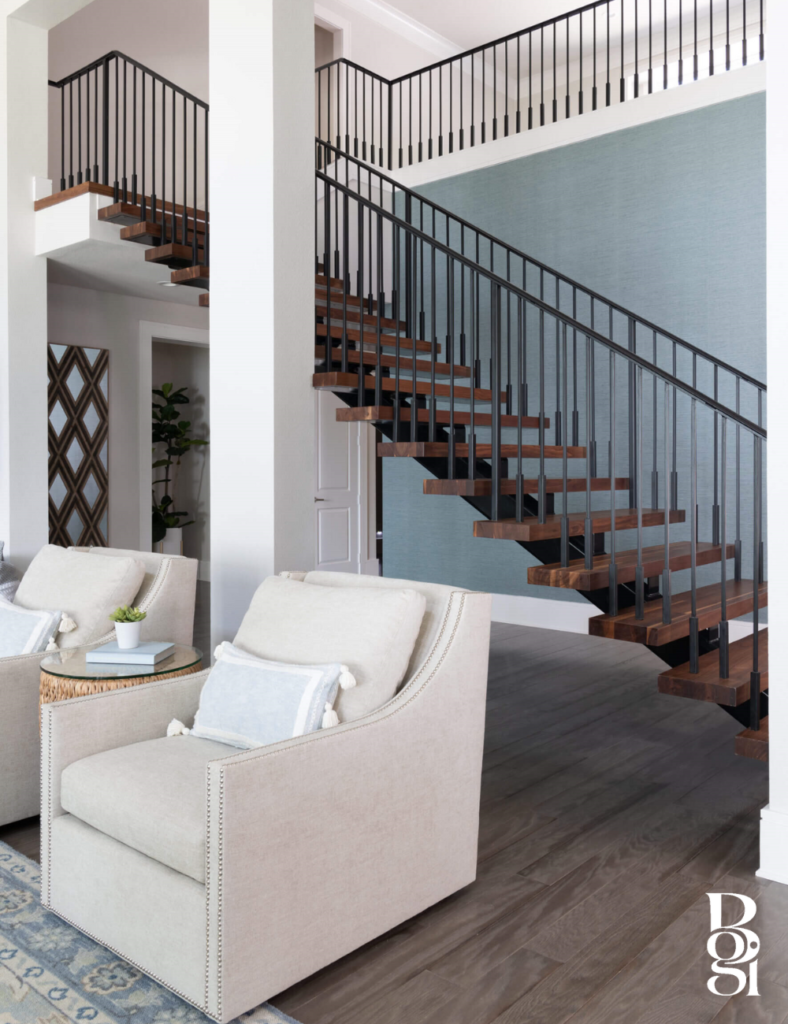 white comfy rocking chairs in front of a modern metal staircase and a blue accent wall behind