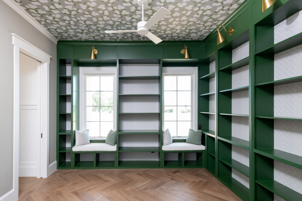remodeled study with green shelving and modern wallpaper on walls and ceiling